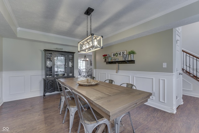 dining area featuring an inviting chandelier, wainscoting, a decorative wall, stairs, and wood finished floors