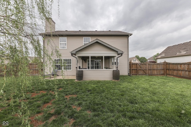 back of house featuring a yard, a chimney, and a fenced backyard