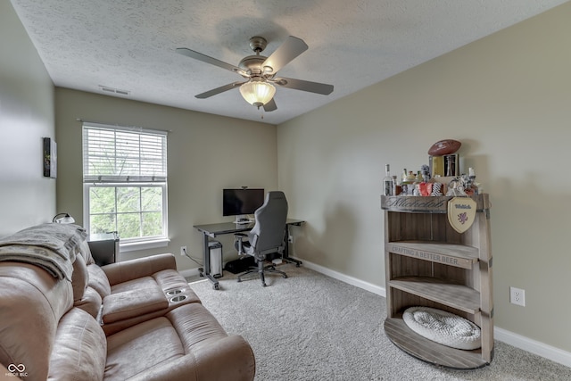 carpeted office space with baseboards, a textured ceiling, and ceiling fan