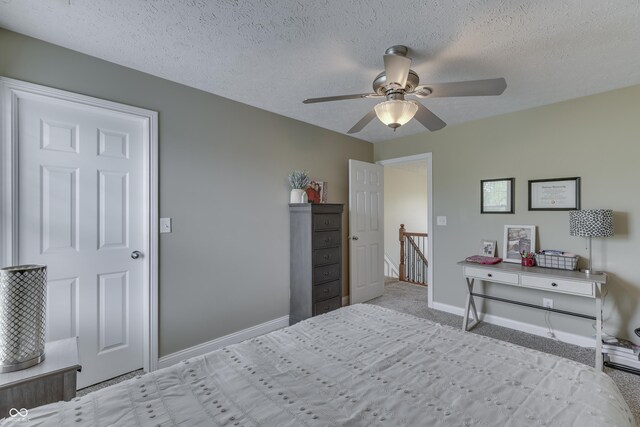 carpeted bedroom featuring baseboards, a ceiling fan, and a textured ceiling