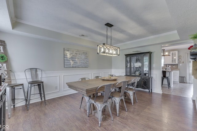 dining space with ornamental molding, wainscoting, wood finished floors, and a decorative wall