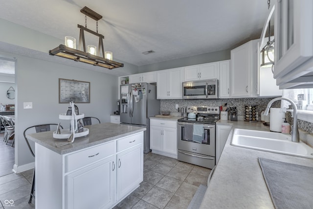 kitchen with a center island, tasteful backsplash, a sink, light countertops, and stainless steel appliances