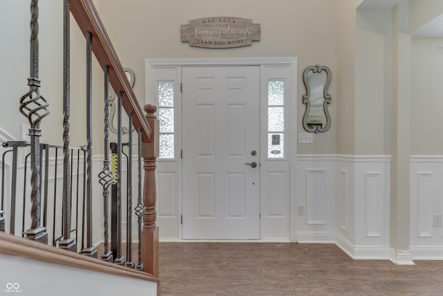 foyer entrance with a wainscoted wall, a healthy amount of sunlight, stairway, and wood finished floors
