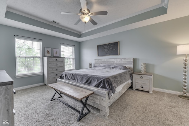 bedroom featuring visible vents, ornamental molding, baseboards, a tray ceiling, and carpet flooring