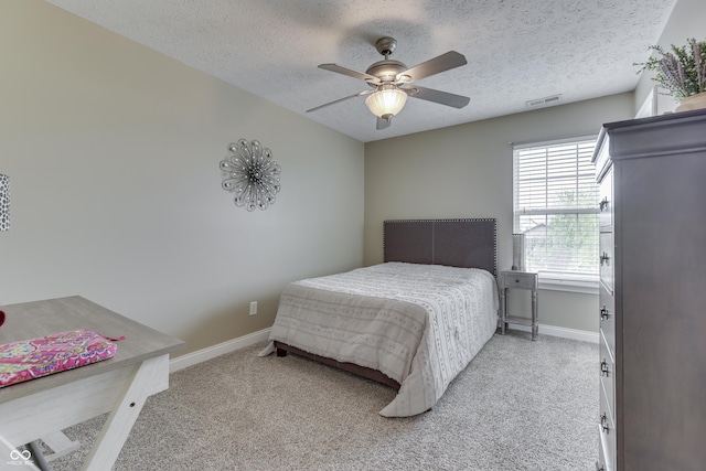 bedroom with baseboards, light colored carpet, a textured ceiling, and visible vents