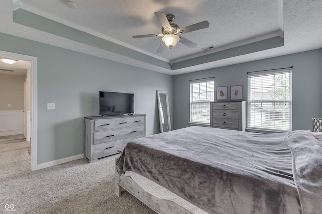 bedroom with a textured ceiling, visible vents, a raised ceiling, carpet floors, and ornamental molding