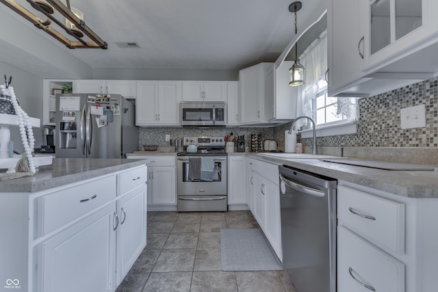 kitchen with a sink, appliances with stainless steel finishes, backsplash, and light countertops