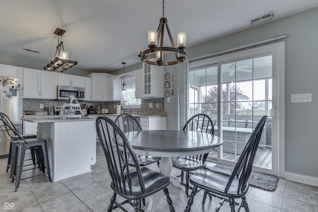 dining space featuring a chandelier, baseboards, visible vents, and light tile patterned flooring