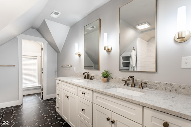 bathroom featuring a sink, baseboards, double vanity, and lofted ceiling