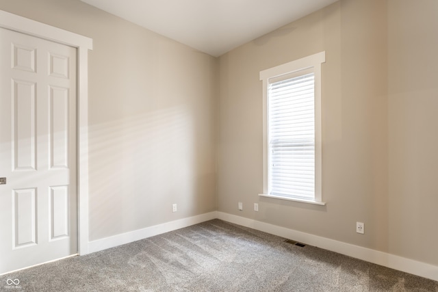 empty room with a healthy amount of sunlight, carpet floors, and visible vents