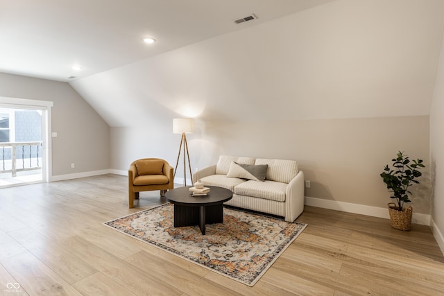 living area featuring baseboards, visible vents, wood finished floors, and lofted ceiling