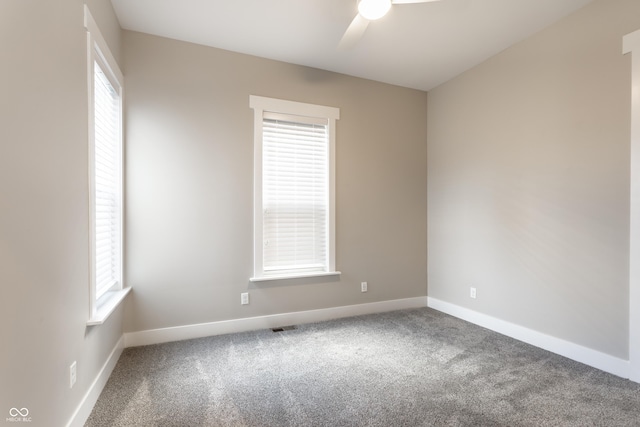carpeted empty room featuring a healthy amount of sunlight, baseboards, ceiling fan, and visible vents