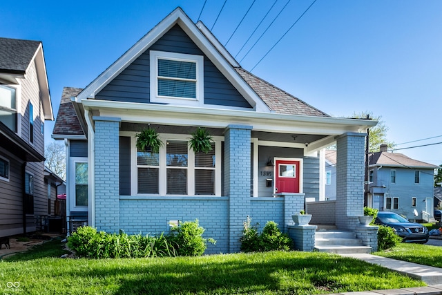 bungalow-style house featuring brick siding, a front lawn, and covered porch