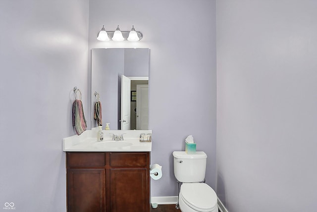 bathroom featuring toilet, vanity, and baseboards