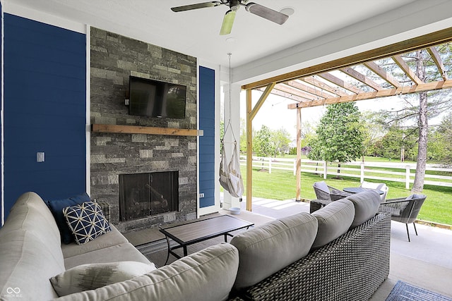 living area featuring a stone fireplace and ceiling fan