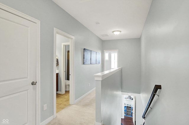corridor featuring an upstairs landing, baseboards, and carpet floors