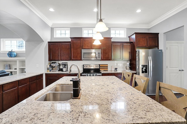 kitchen featuring appliances with stainless steel finishes, a sink, decorative light fixtures, light stone counters, and backsplash