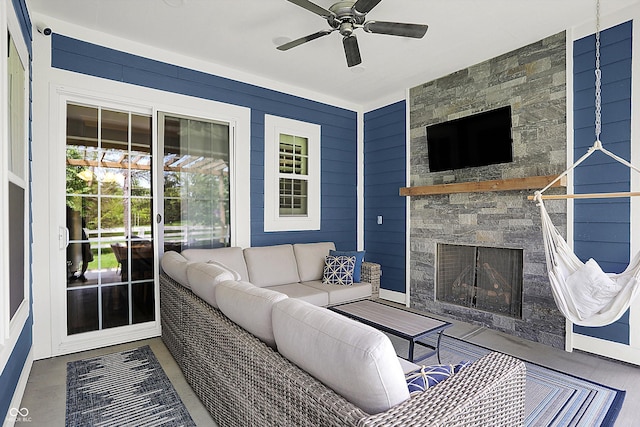 living room featuring a ceiling fan, an outdoor stone fireplace, and baseboards