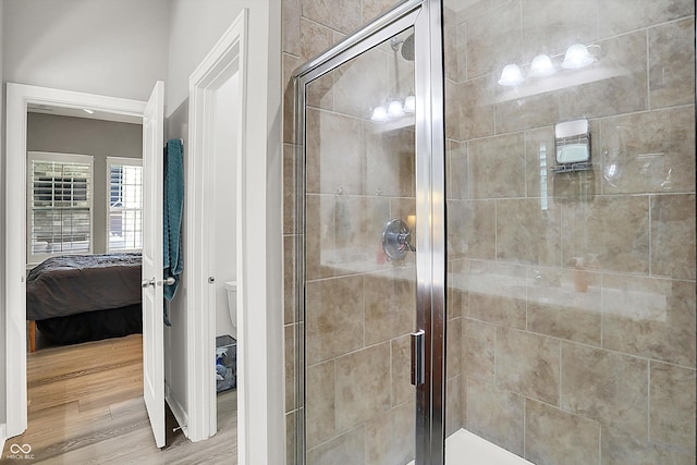 ensuite bathroom featuring a shower stall, toilet, and wood finished floors