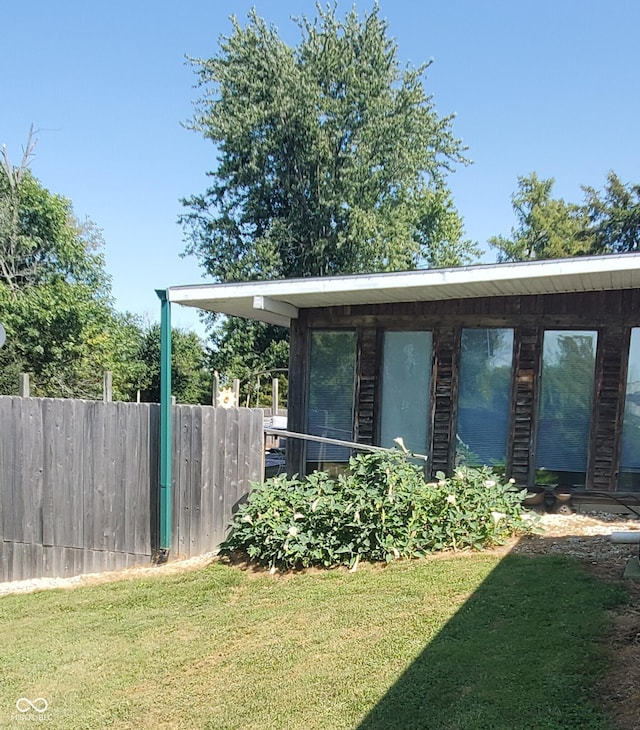 view of home's exterior with a lawn and fence