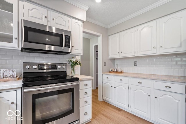 kitchen featuring appliances with stainless steel finishes, light countertops, a textured ceiling, white cabinetry, and backsplash