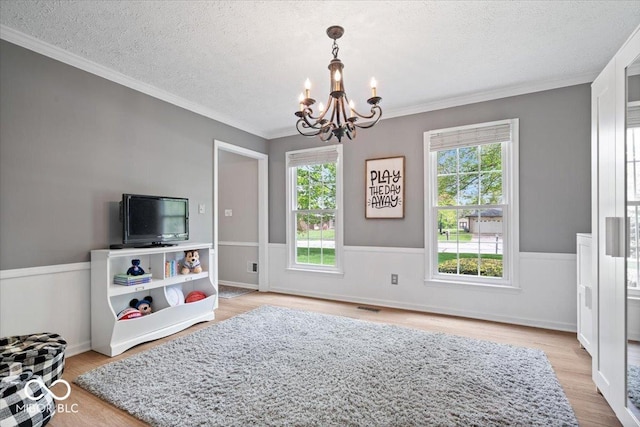 interior space with crown molding, a textured ceiling, wood finished floors, and a notable chandelier