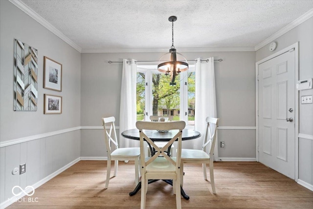 dining space featuring an inviting chandelier, a textured ceiling, crown molding, and wood finished floors