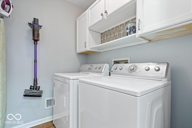 washroom featuring baseboards, visible vents, cabinet space, and washer and clothes dryer