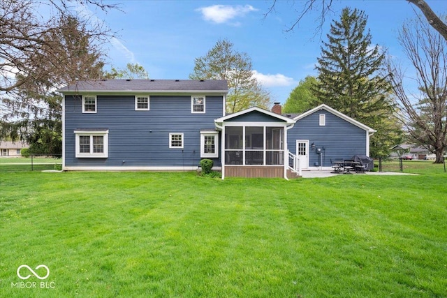 rear view of house with a lawn, a patio, a chimney, and a sunroom