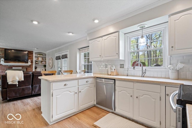 kitchen with a peninsula, plenty of natural light, a textured ceiling, a sink, and stainless steel appliances