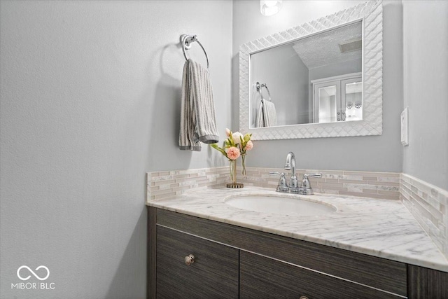 bathroom with vanity, a textured ceiling, and backsplash