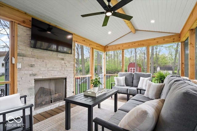sunroom with beamed ceiling, a ceiling fan, and an outdoor living space with a fireplace