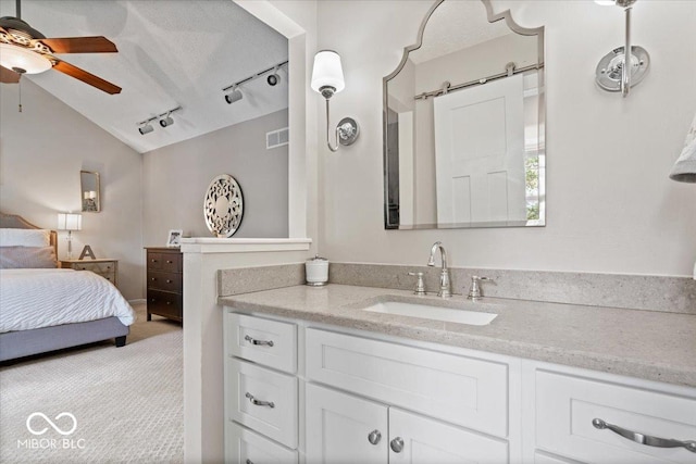 bathroom with vanity, rail lighting, a ceiling fan, vaulted ceiling, and visible vents