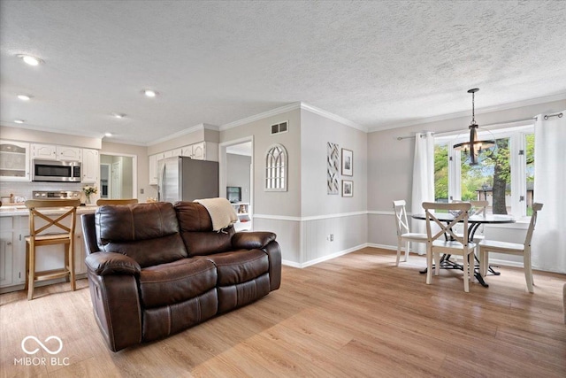 living area with baseboards, light wood-type flooring, a textured ceiling, and visible vents