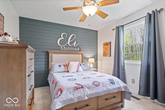 bedroom with carpet floors, visible vents, wooden walls, a textured ceiling, and a ceiling fan