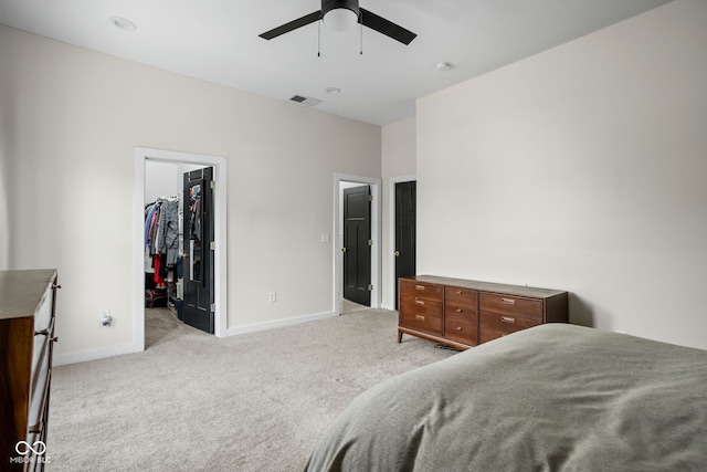 bedroom featuring ceiling fan, visible vents, light colored carpet, baseboards, and a spacious closet