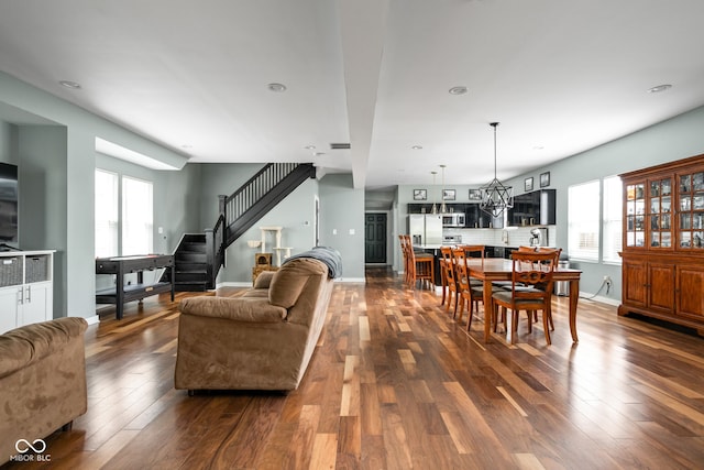 living area featuring stairway, baseboards, plenty of natural light, and dark wood-type flooring