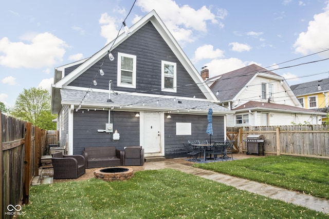 back of property with a fenced backyard, an outdoor living space with a fire pit, a yard, and a patio area