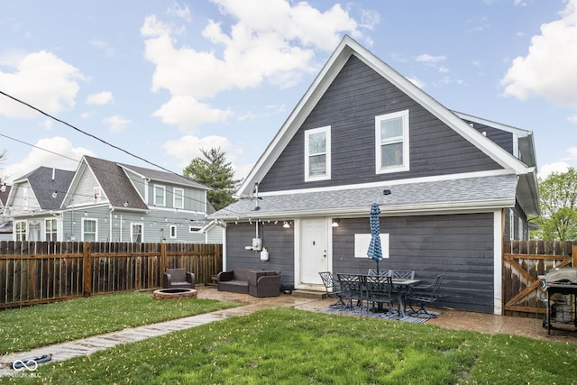rear view of property featuring a patio, a fenced backyard, roof with shingles, and a yard