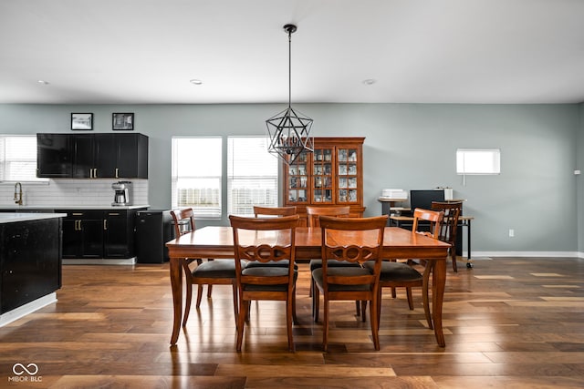 dining area featuring a healthy amount of sunlight, an inviting chandelier, and dark wood finished floors