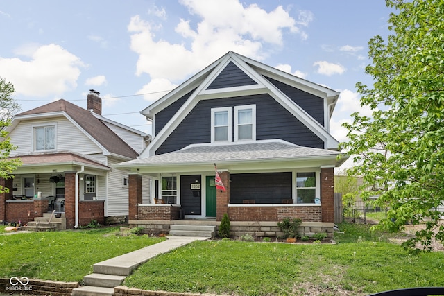 view of front of property with covered porch, brick siding, fence, and a front lawn