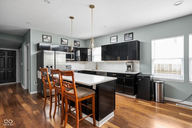 kitchen with a breakfast bar area, visible vents, appliances with stainless steel finishes, light countertops, and dark cabinets