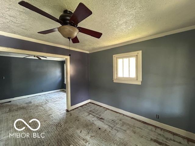 unfurnished room with crown molding, a textured ceiling, a ceiling fan, baseboards, and wood finished floors