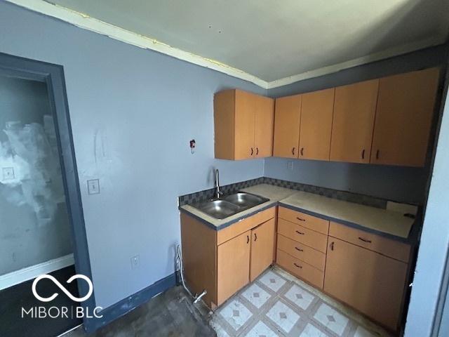 kitchen with a sink, baseboards, light brown cabinets, and light floors