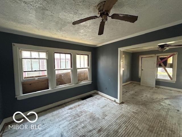empty room featuring a textured ceiling, ceiling fan, and a wealth of natural light