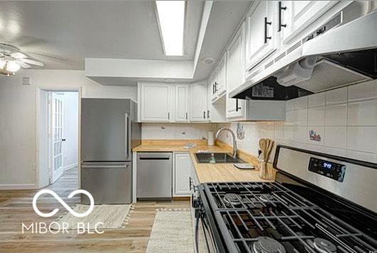 1391 S River Rd, Covington, IN 47932 - kitchen featuring a ceiling fan, a sink, under cabinet range hood, light wood-style floors, and stainless steel appliances