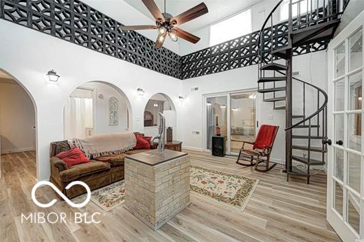 1391 S River Rd, Covington, IN 47932 - living area featuring arched walkways, stairs, a ceiling fan, wood finished floors, and a towering ceiling