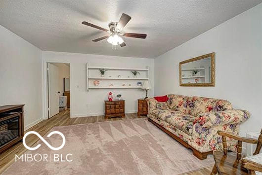1391 S River Rd, Covington, IN 47932 - living room featuring baseboards, a textured ceiling, ceiling fan, and wood finished floors