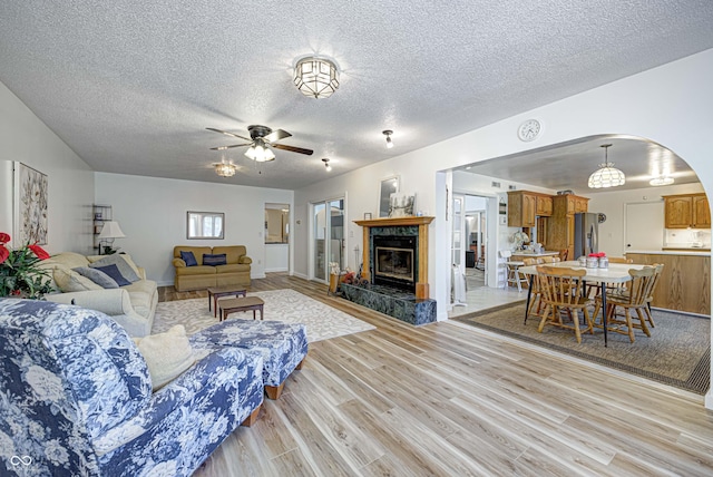 1391 S River Rd, Covington, IN 47932 - living room featuring a ceiling fan, a textured ceiling, arched walkways, and light wood finished floors