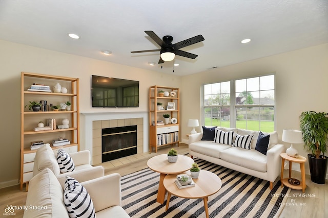 living area with ceiling fan, wood finished floors, a tile fireplace, baseboards, and recessed lighting